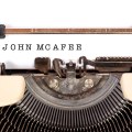 Grafika przedstawiająca maszynę do pisania z kartką, na której umieszczono napis John McAfee